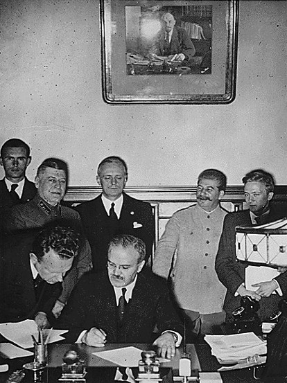 Image - Viacheslav Molotov signs the German-Soviet non-aggression pact (Ribbentrop and Stalin in the background).